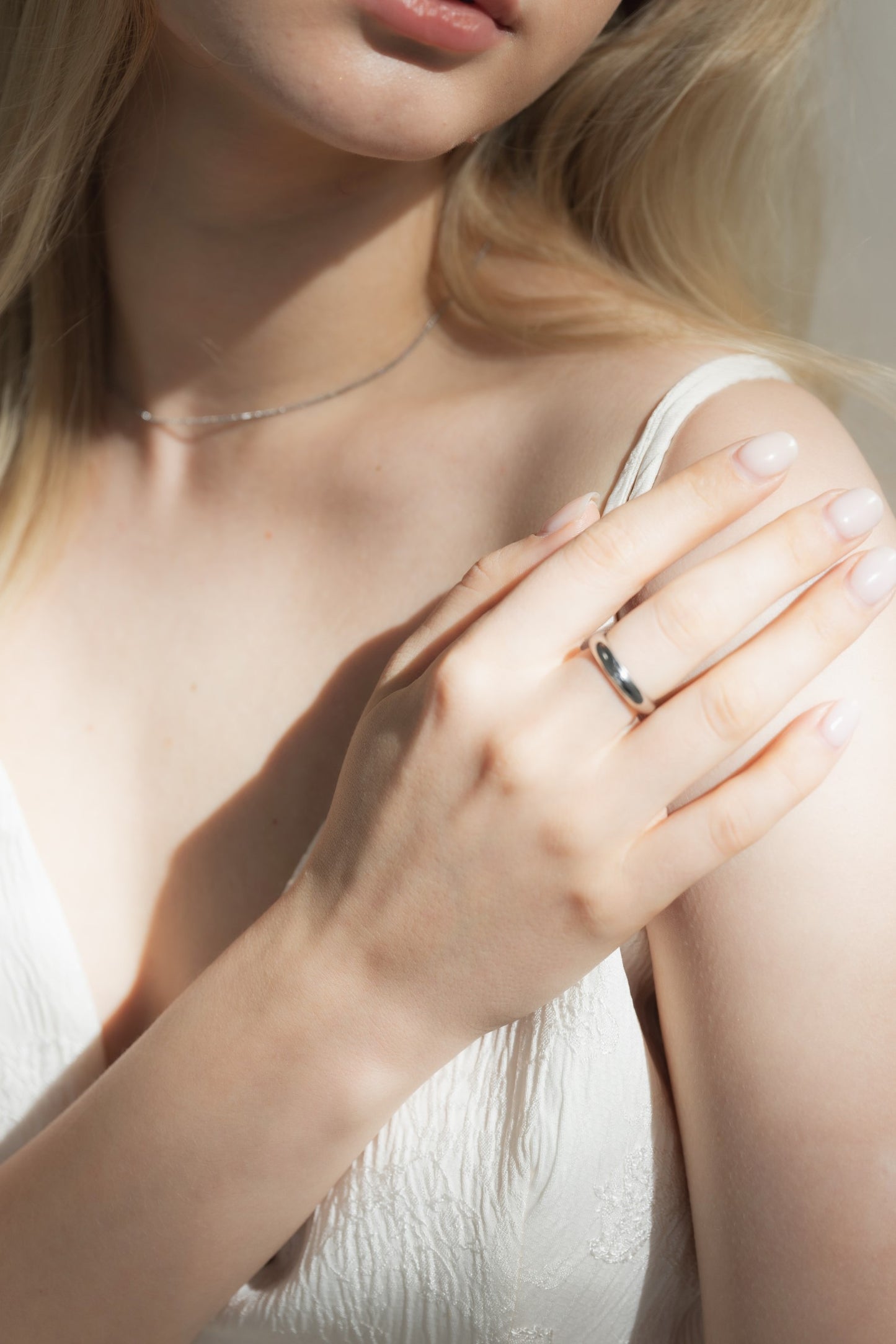 4mmプレーンリングを着用した女性の手元のクローズアップ。シンプルで存在感のあるステンレス製リング。