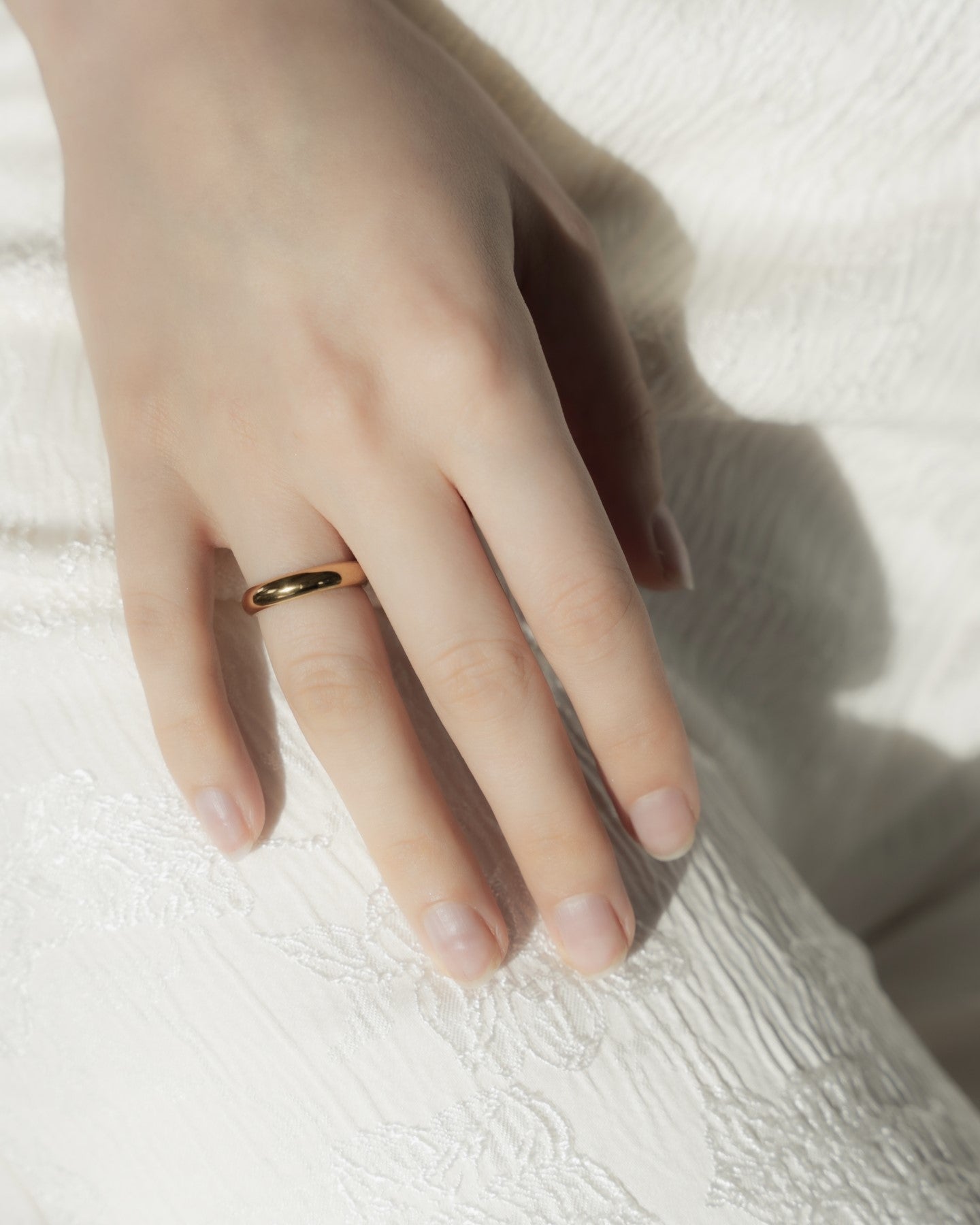 4mmプレーンリングを着用した女性の手元のクローズアップ。シンプルで存在感のあるステンレス製リング。
