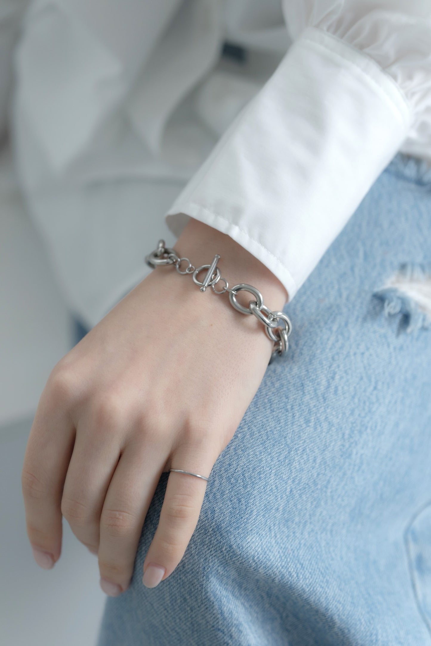 チェーンマントルブレスレットを着用した女性の手首のクローズアップ。重厚感のあるマントルデザインが特徴のステンレス製ブレスレット。