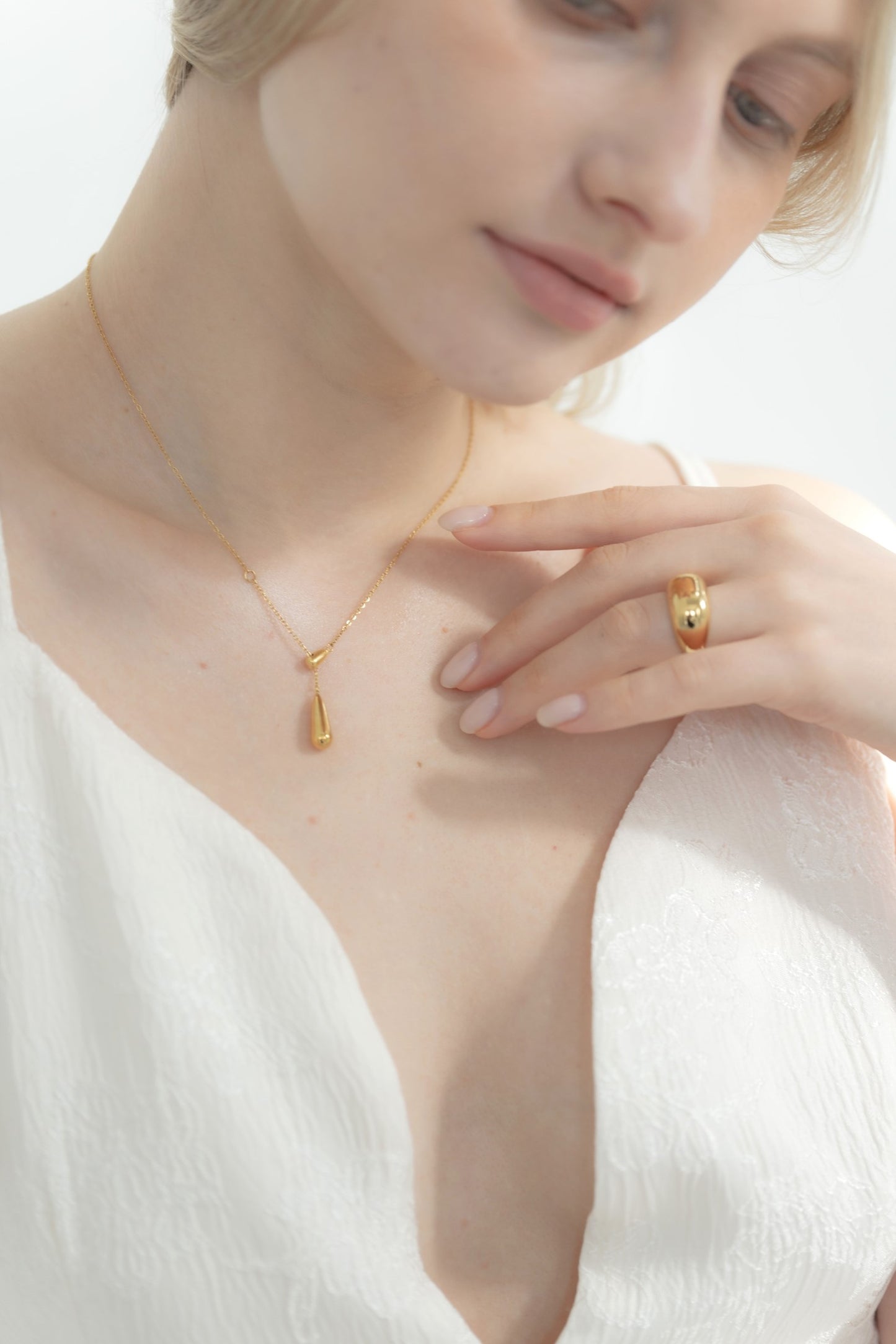 日常使いとしてドロップトップネックレスを着用する女性。シンプルでありながら洗練されたデザインが日常の装いを引き立てる。