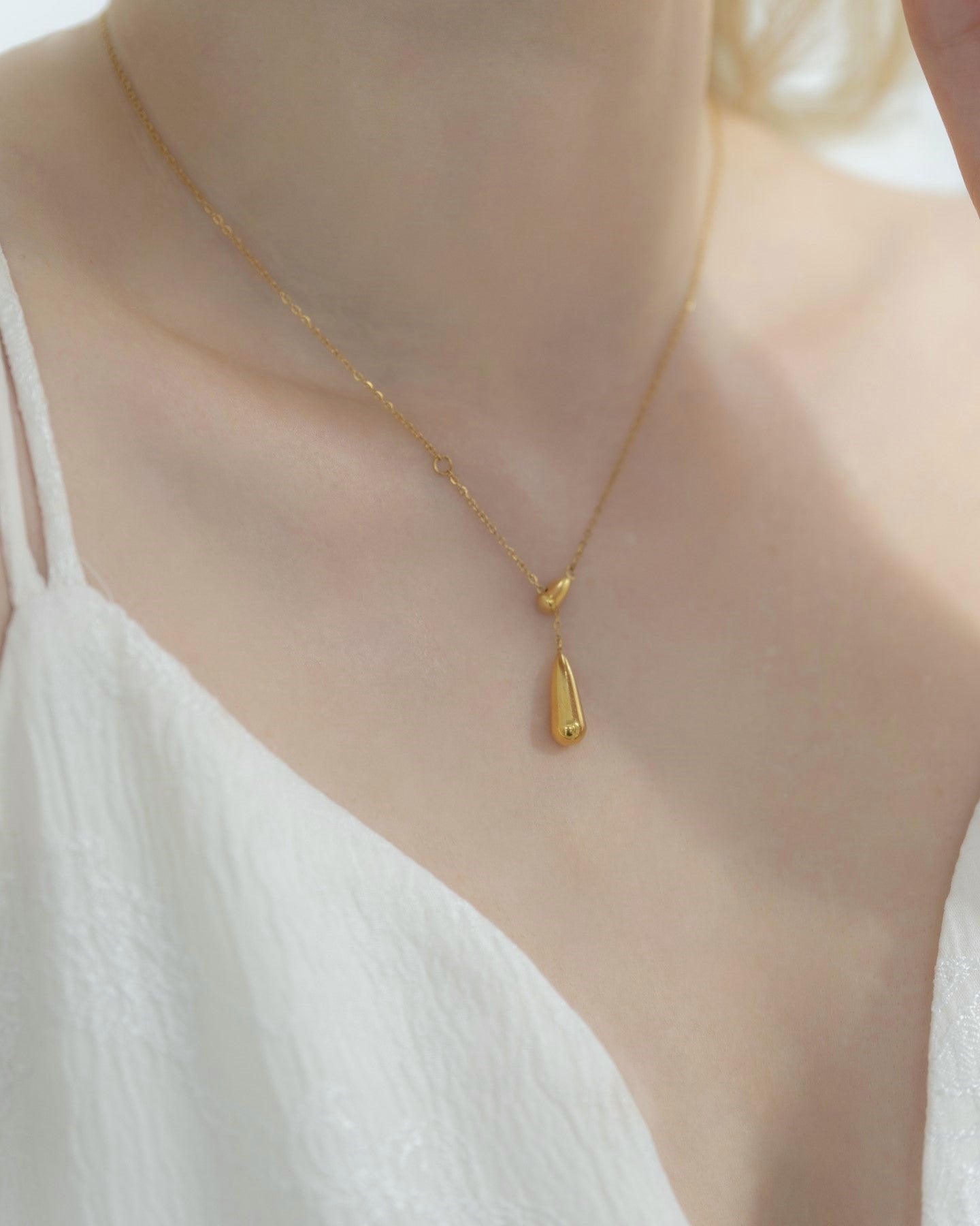 ドロップトップネックレスを着用した女性の首元のクローズアップ。シンプルで優雅なドロップ型デザインが特徴のステンレス製ネックレス。
