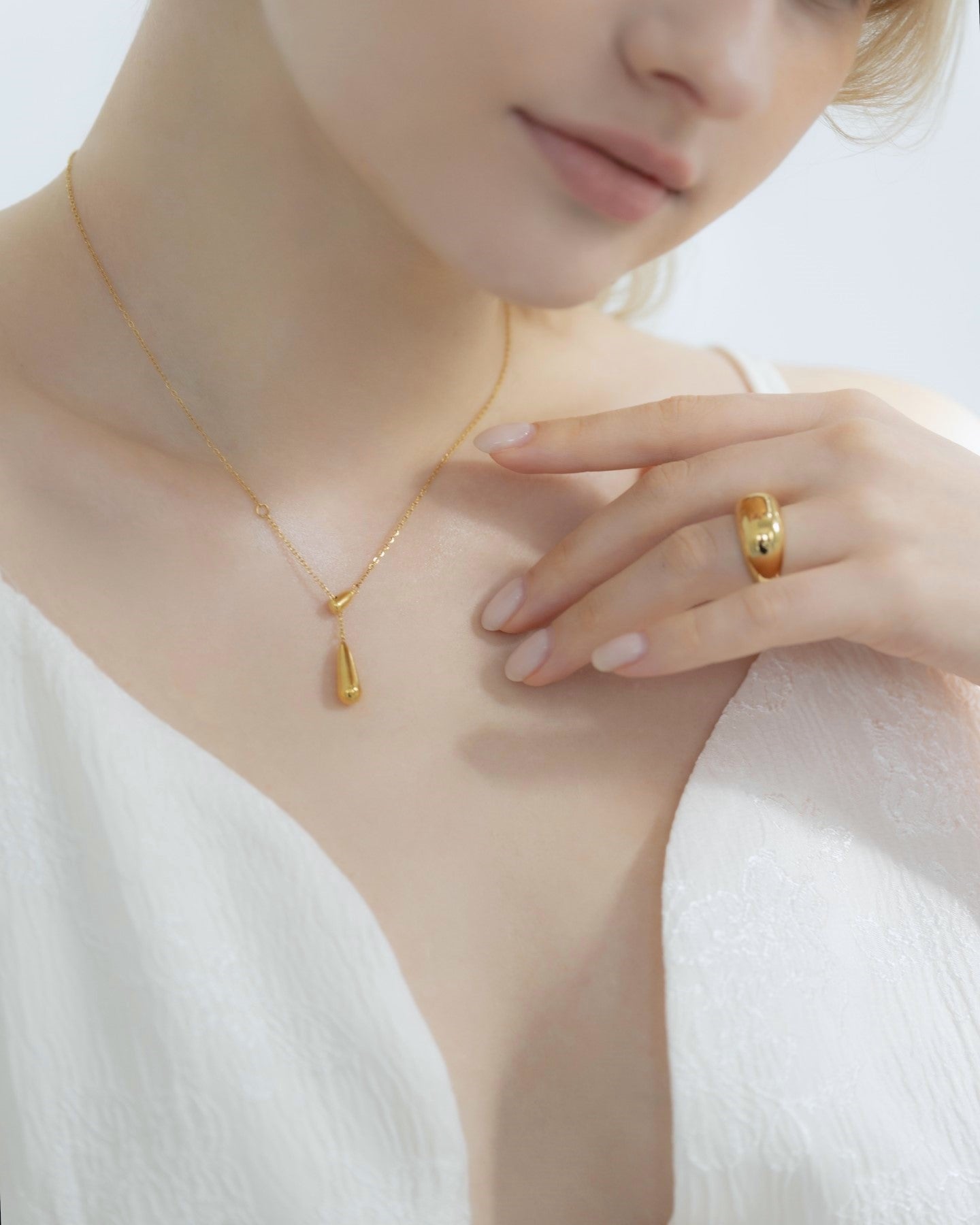 他のジュエリーと一緒にドロップトップネックレスを着用する女性。重ね付けにも最適で、スタイルを引き立てるアクセサリー。