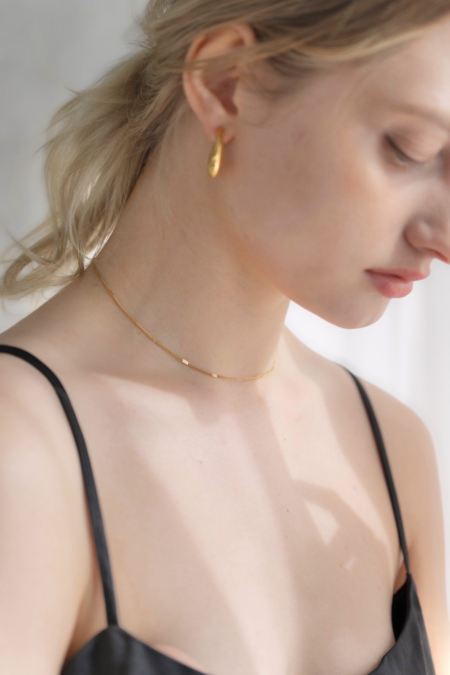 他のジュエリーと一緒にシンプルチェーンネックレスを着用する女性。重ね付けにも最適な、ミニマルでスタイリッシュなデザイン。