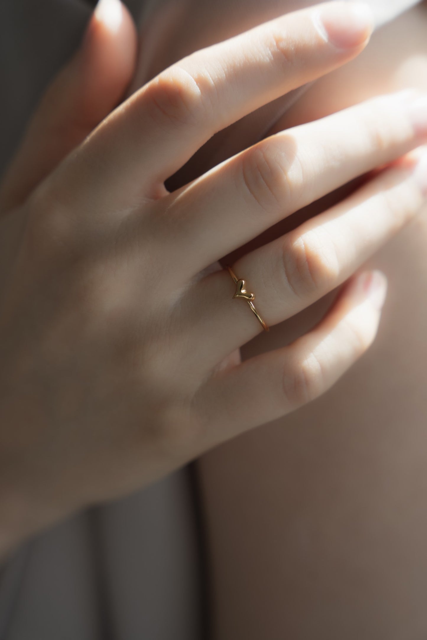 ミニハートリングを着用した女性の横顔。小ぶりでシンプルなデザインが、日常使いにも最適なアクセサリー。
