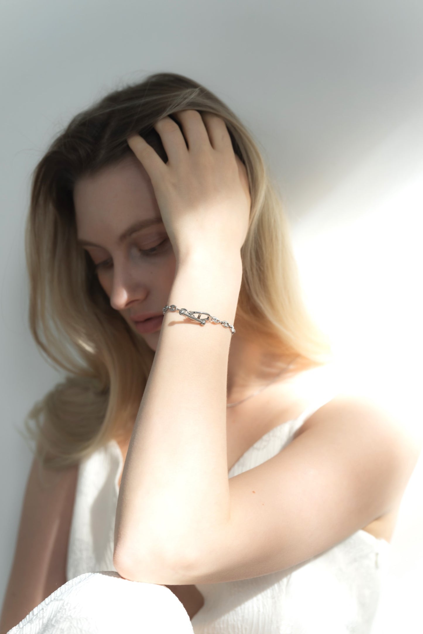 モチーフチェーンブレスレットを着用した女性の横顔。エレガントで個性的なモチーフが手元を美しく飾る。