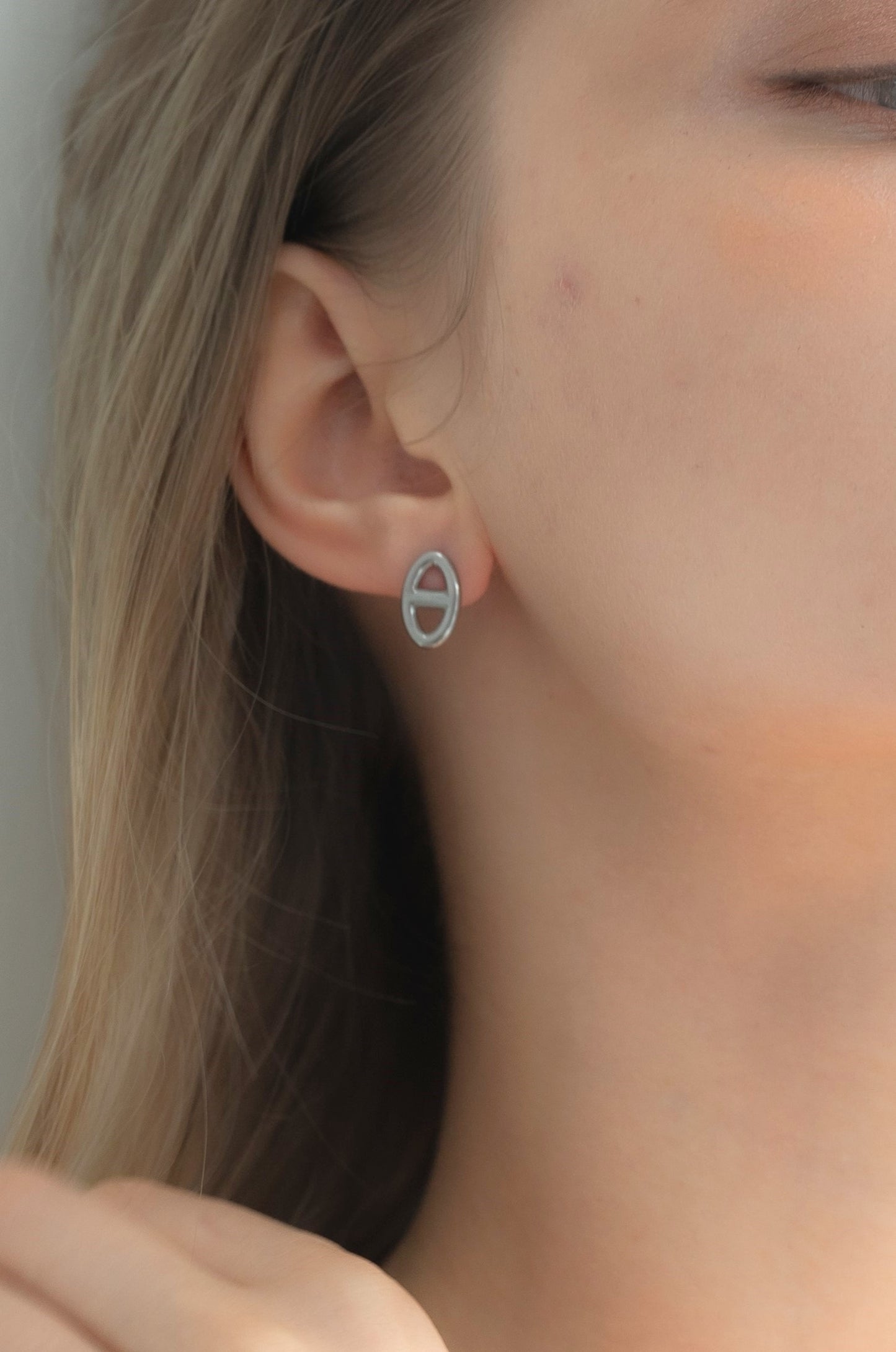 モチーフピアスを着用した女性の耳元のクローズアップ。ステンレス製で個性的なデザインのアクセサリー。
