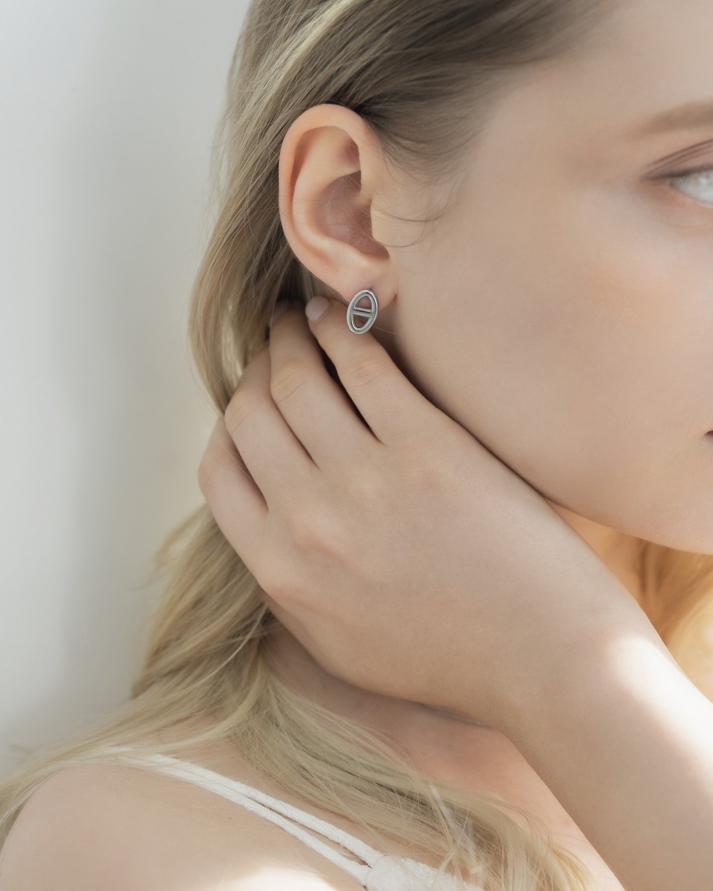 モチーフピアスを着用した女性の耳元のクローズアップ。ステンレス製で個性的なデザインのアクセサリー。