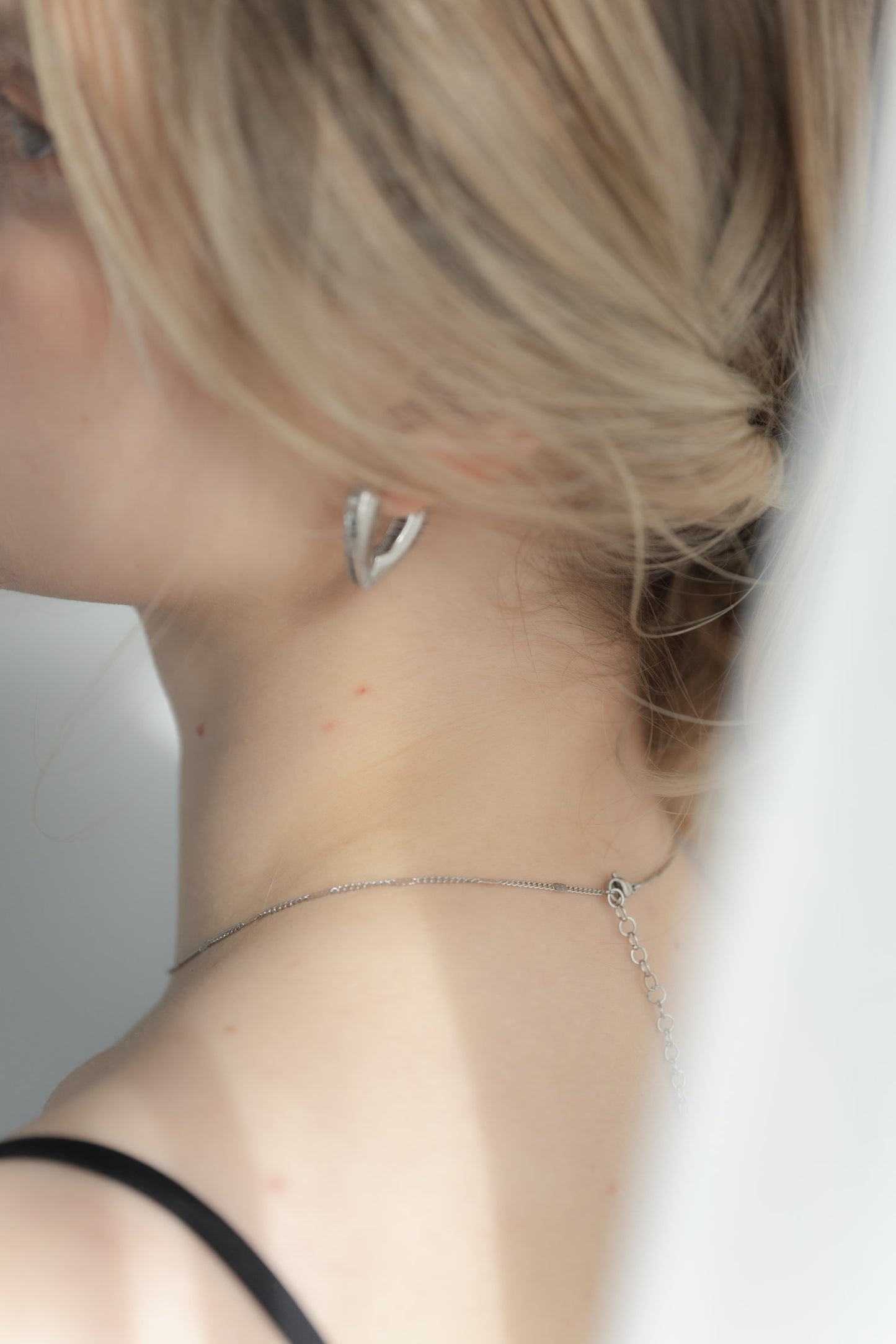 ニュアンスハートフープピアスを着用した女性の耳元のクローズアップ。エレガントで愛らしいハート型のステンレス製ピアス。