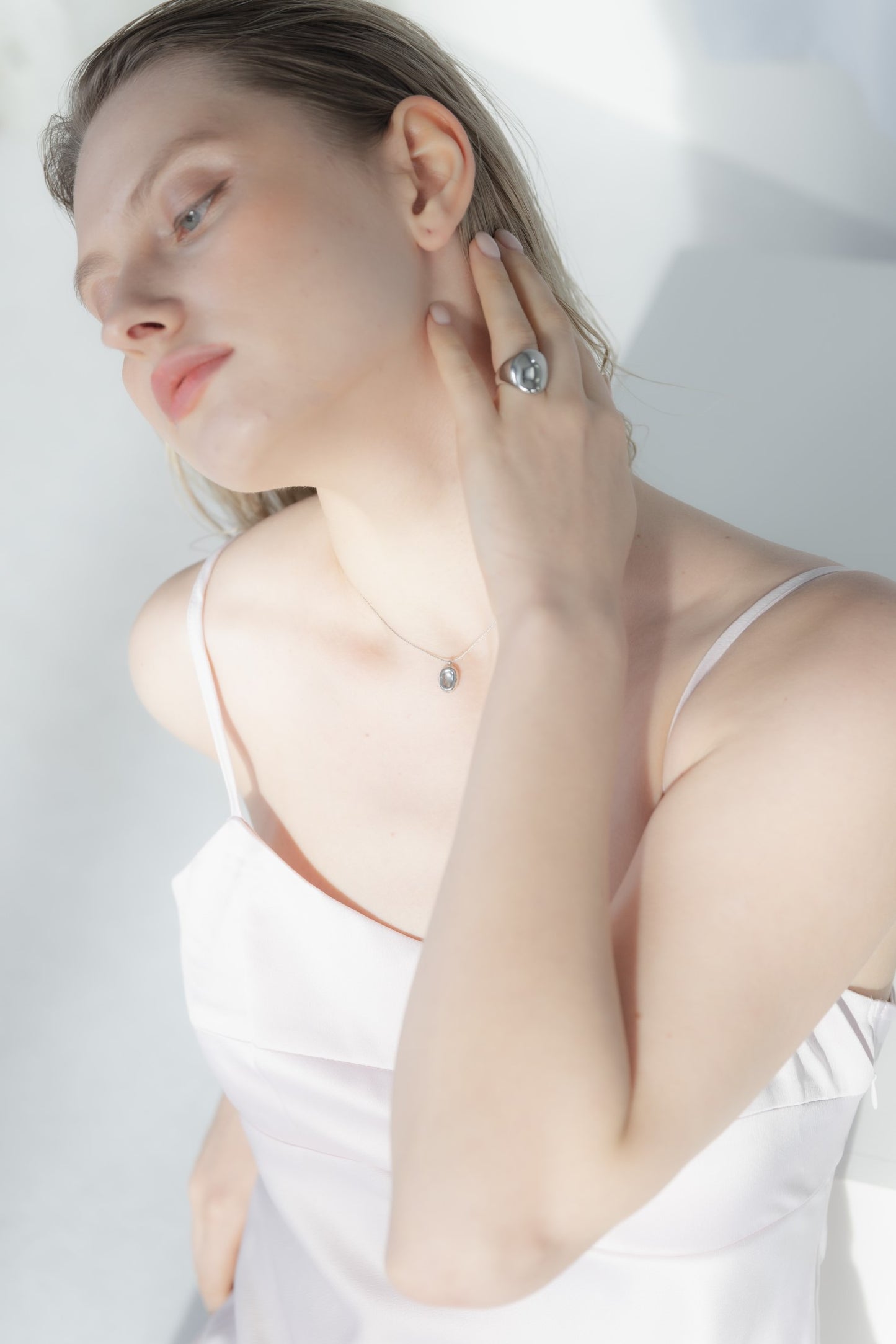 他のジュエリーと一緒にオーバルトップネックレスを着用する女性。重ね付けにもぴったりなモダンでエレガントなデザイン。