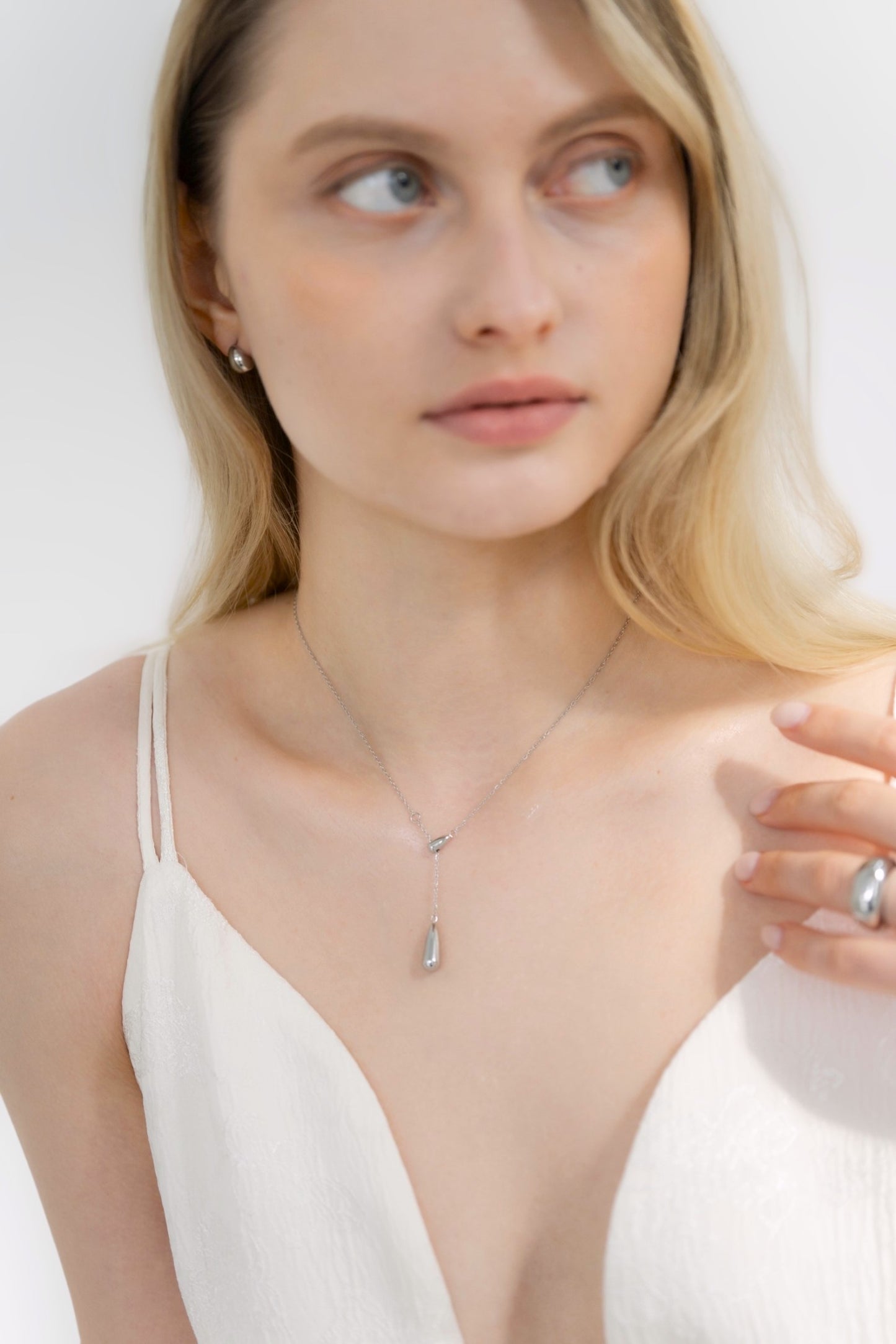 ドロップトップネックレスを着用した女性の首元のクローズアップ。シンプルで優雅なドロップ型デザインが特徴のステンレス製ネックレス。
