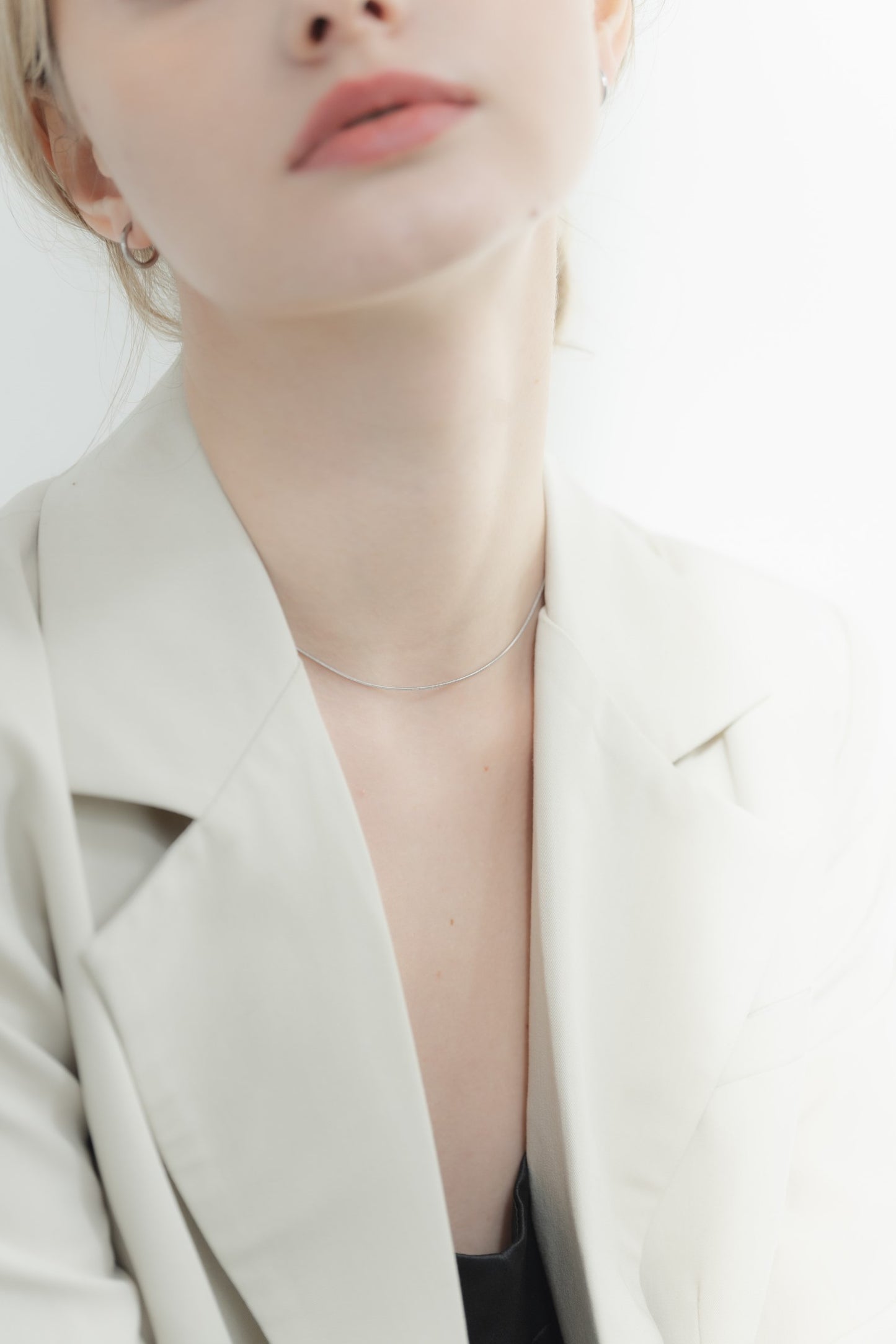 他のジュエリーと一緒にシンプル1mmネックレスを着用する女性。重ね付けにも最適で、コーディネートに合わせやすいアクセサリー。
