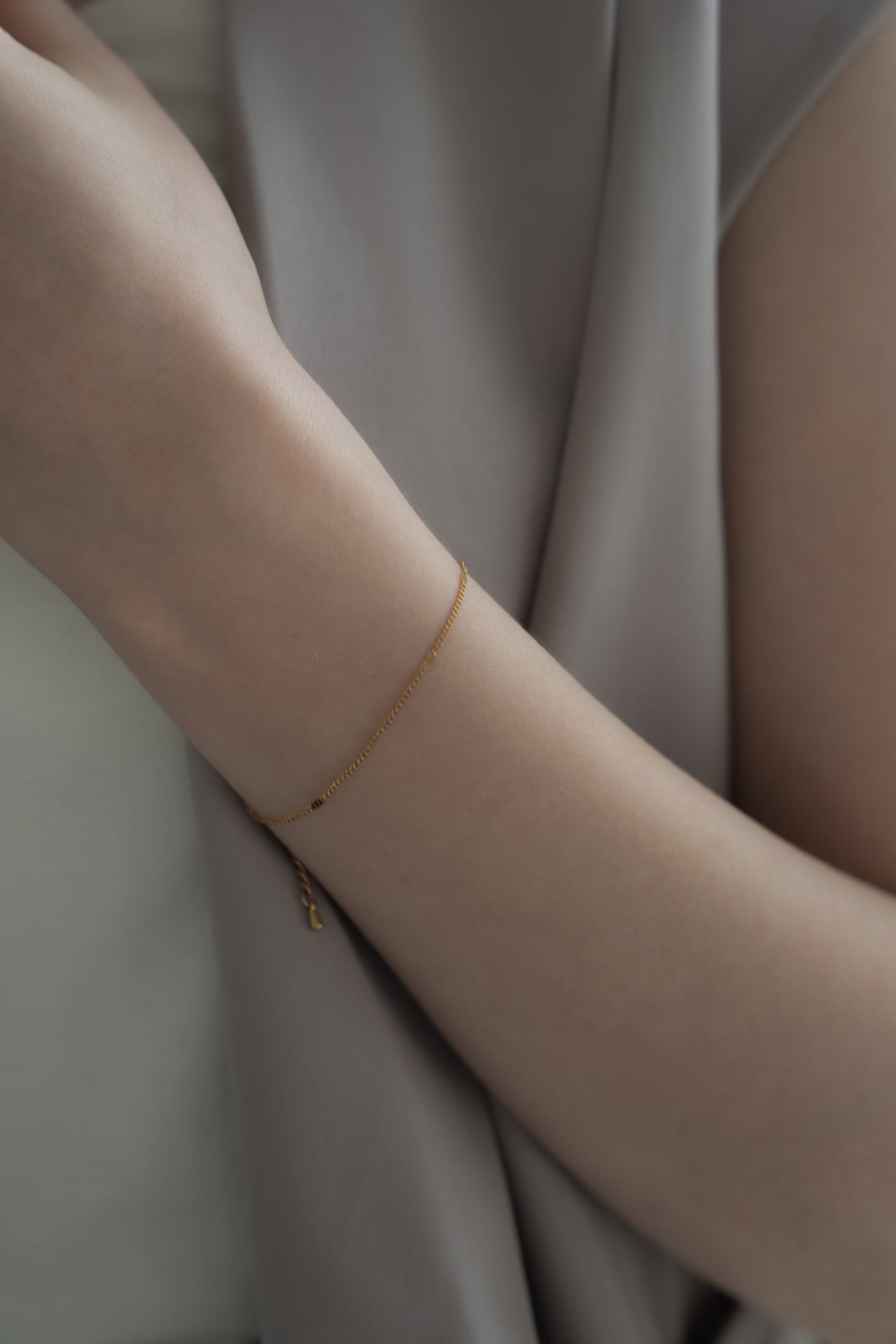 ファッションスタイルに合わせてシンプルチェーンブレスレットを着用した女性。ミニマルでありながらスタイリッシュなデザインが引き立つ。