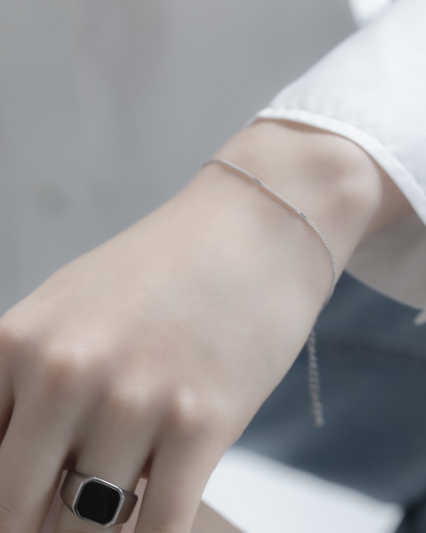 シンプルチェーンブレスレットを着用した女性の手首のクローズアップ。洗練されたデザインのステンレス製ブレスレットが手元を美しく飾る。