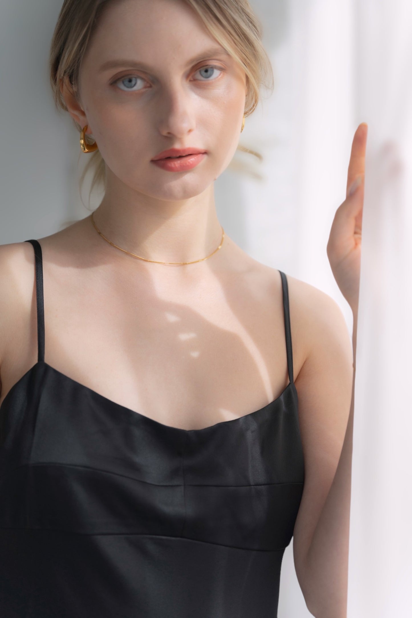 シンプルチェーンネックレスを着用した女性の首元のクローズアップ。洗練されたミニマルなデザインが魅力のステンレス製ネックレス。