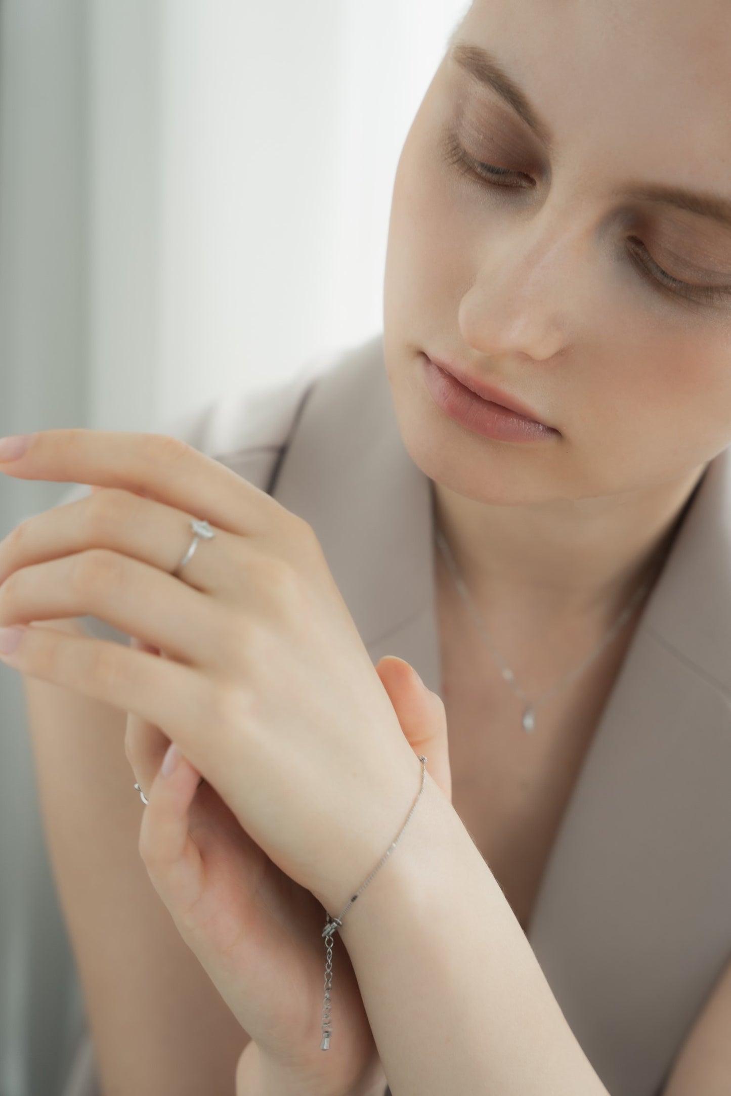 他のジュエリーと一緒にシンプルチェーンブレスレットを着用する女性。重ね付けにも最適なシンプルでエレガントなデザイン。