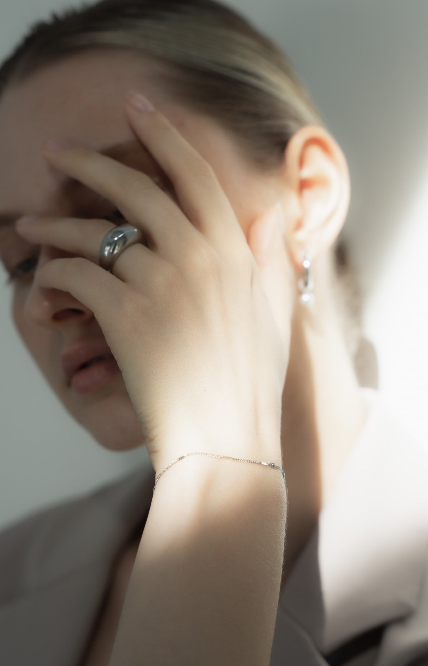 シンプルチェーンブレスレットを着用した女性の手首のクローズアップ。洗練されたデザインのステンレス製ブレスレットが手元を美しく飾る。