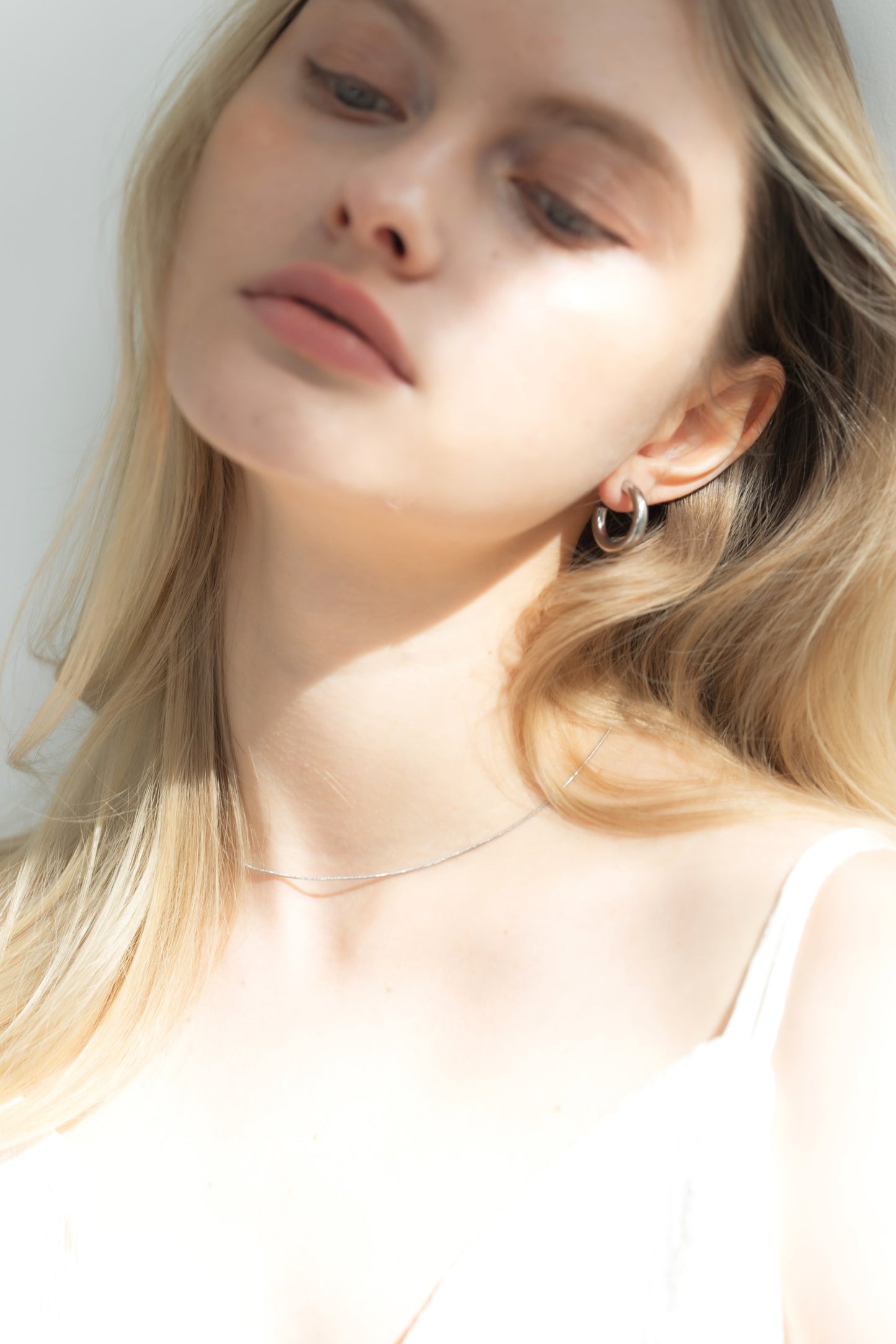 他のジュエリーと合わせてシンプルフープピアスを着用する女性。シンプルながらも個性を引き立てるコーディネート。
