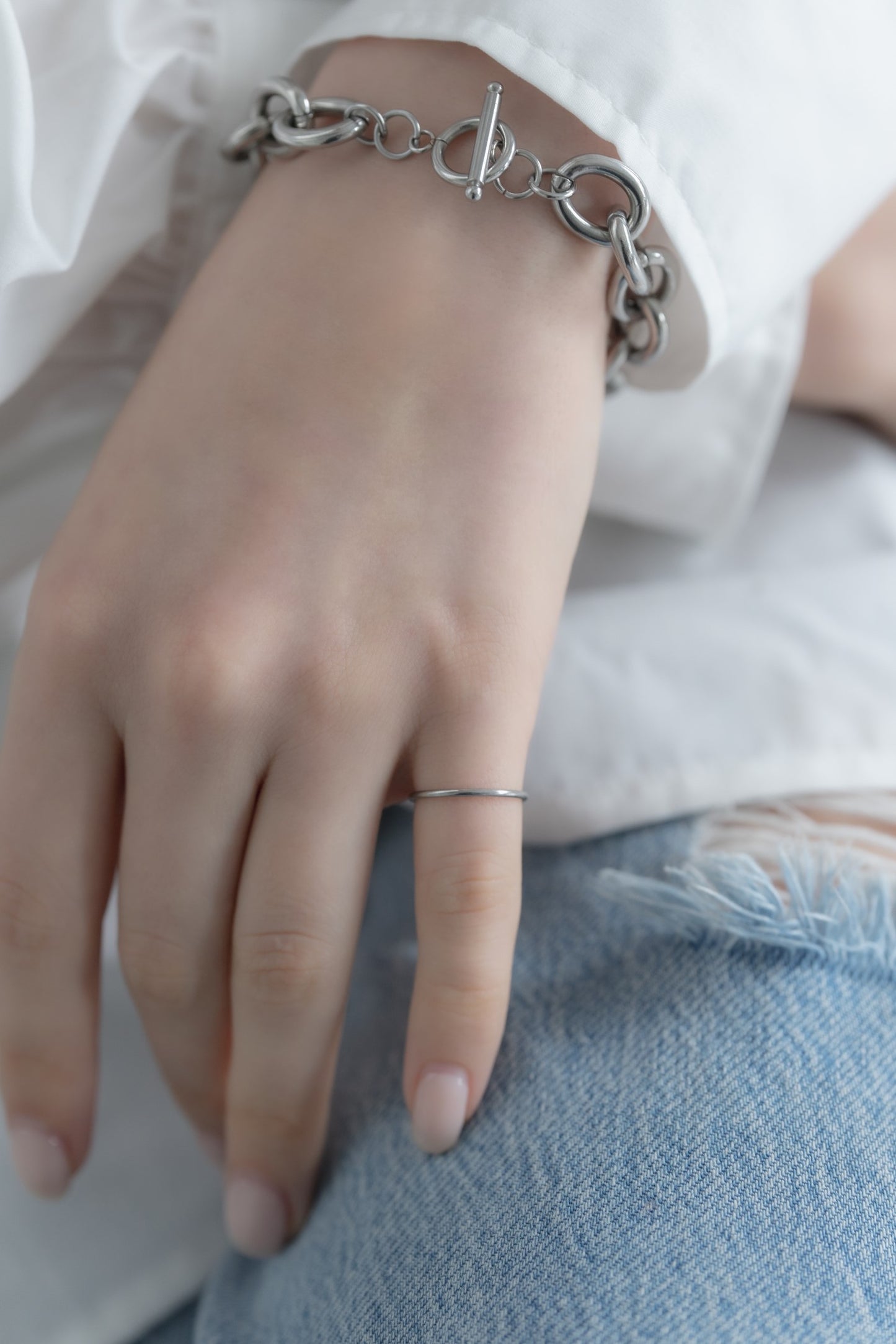シンプルピンキーリングを着用した女性の手元のクローズアップ。洗練されたステンレス製デザインのピンキーリング。