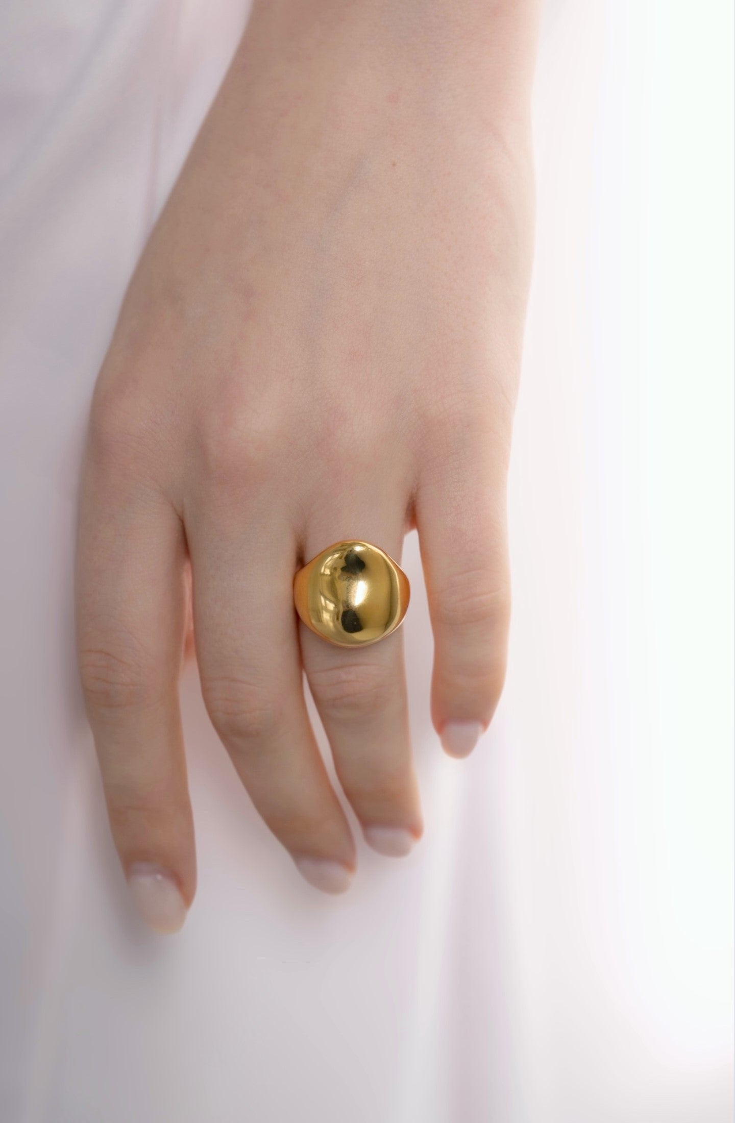 ボリュームニュアンスリングを着用した女性の手元のクローズアップ。高品質のステンレス製で、エレガントなデザインのアクセサリー。
