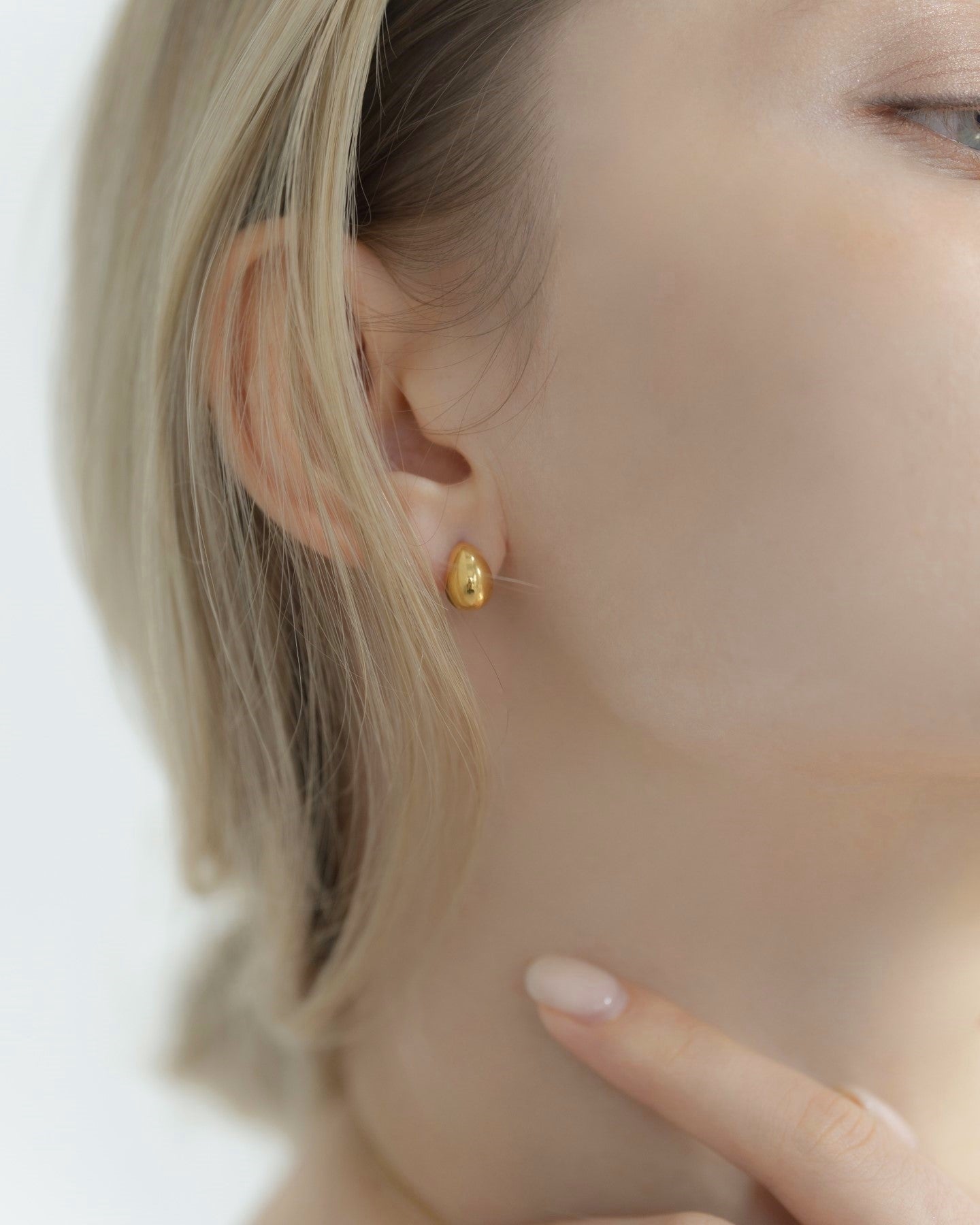 ドロップピアスを着用した女性の横顔。シンプルでありながら存在感のあるデザインが際立つアクセサリー。