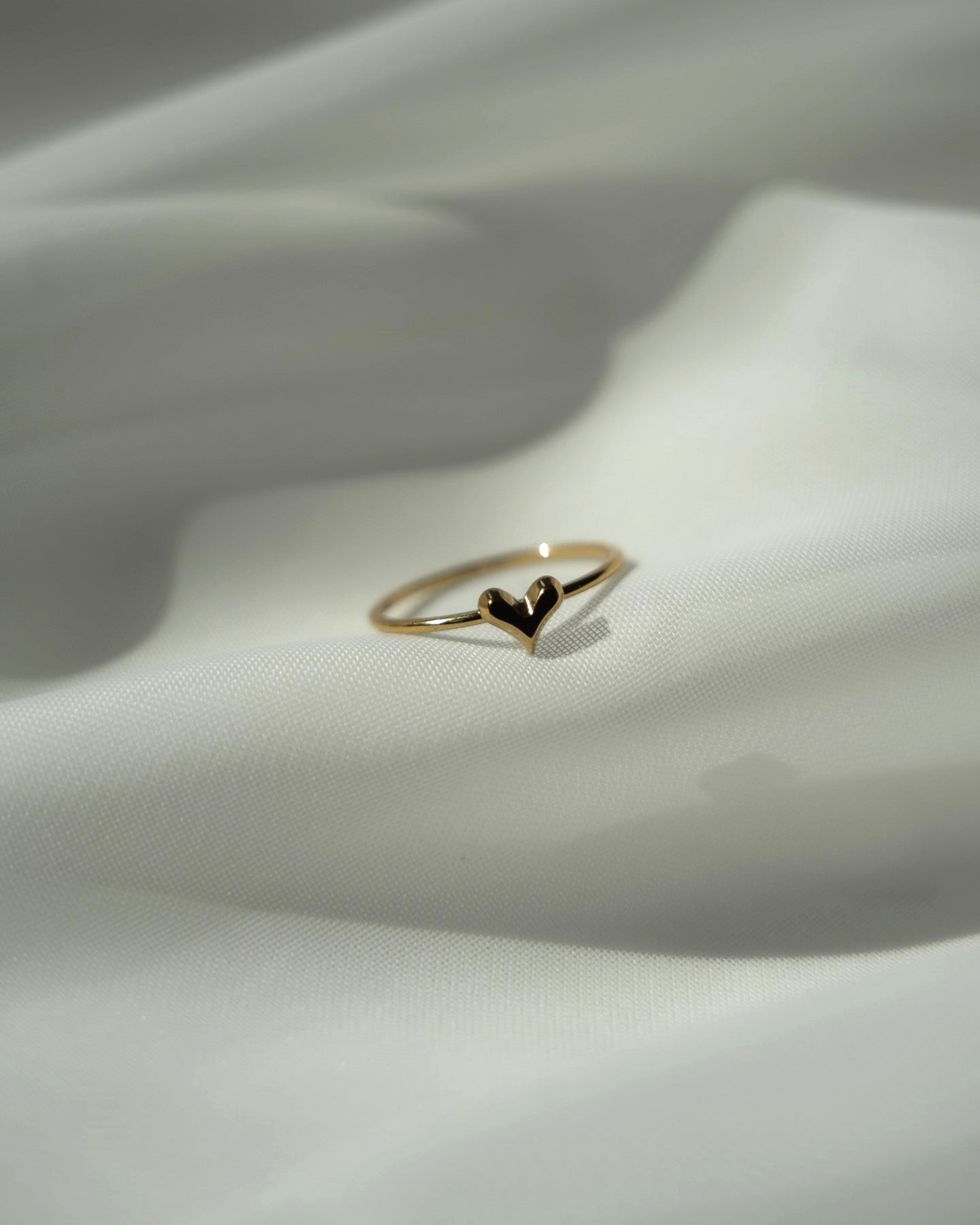 ステンレス製のミニハートリングの平置き撮影。小さなハートモチーフが際立つシンプルで愛らしいデザインのアクセサリー。